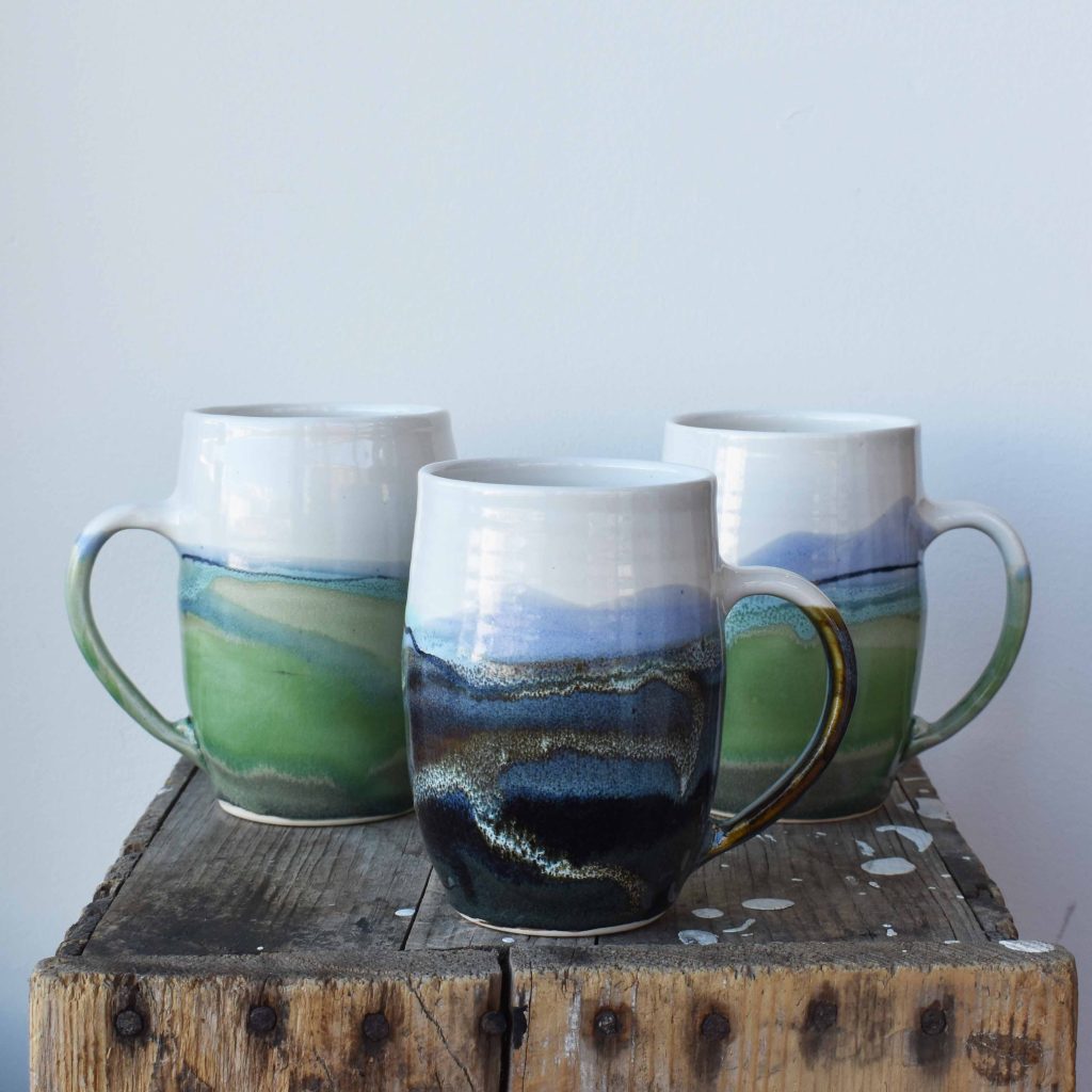 landscape green and blue pottery tall mug handcrafted with white clay ceramic by Bronwyn Arundel at h squared gallery in Fernie