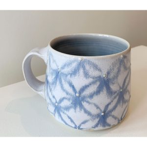 Katriona Drijber's yellow and black moth with gold dots in blue snowflake or floral pattern porcelain mug at h squared gallery in Fernie, BC