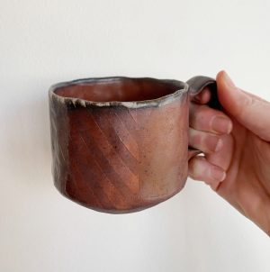 Heather Dynes Smit, hand built potter and wood fired ceramic mug with striped pattern in dark reds and browns