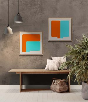 Two geometrical paintings in orange and tourquoise placed above a bench in an entry